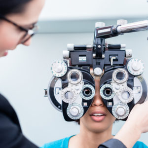 Optometrist and woman at eye examination with phoropter